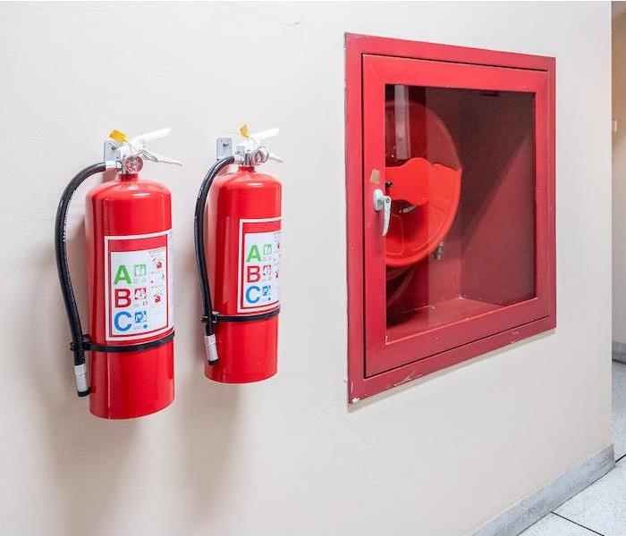 two fire extinguisher hanging on a tan interior wall