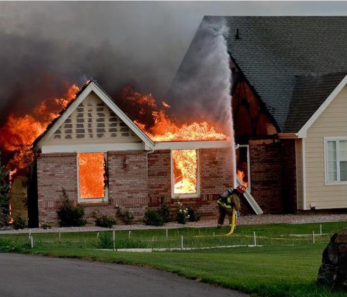 < img src =”firehome.jpg” alt = "firefighter with water hose trying to put out large flames engulfing brick home >