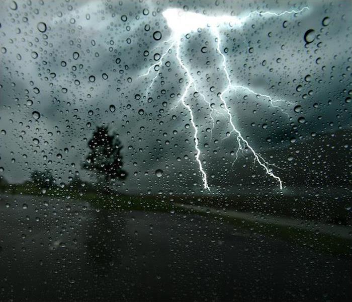 a large lighting strike just in front of person driving down road